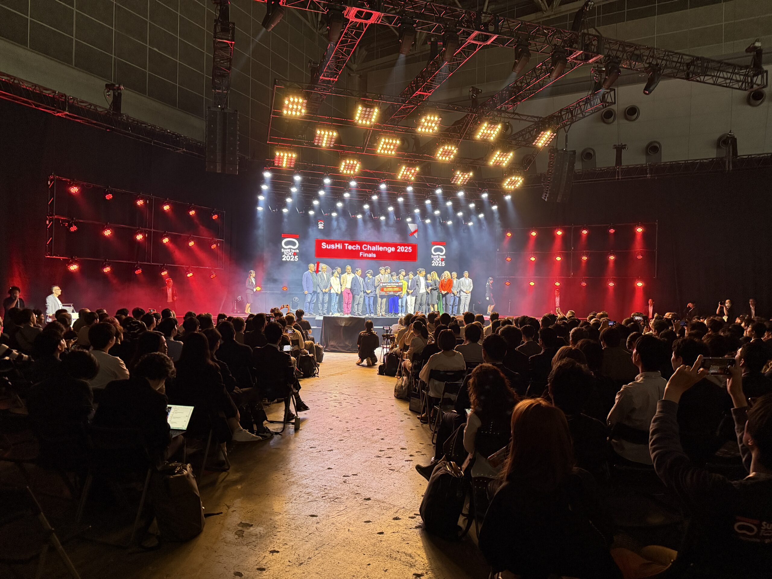 スタートアップ、VC、投資家、市民が交わり過去最大規模となった「SusHi Tech Tokyo 2025」 【イベントレポート】 DAY 1｜都市×スタートアップ　共創する未来都市 都庁が掲げる“未来都市”ビジョン 小池百合子東京都知事の開幕スピーチでは、「最先端テクノロジーで持続可能な都市を実現する」という明確な宣言があり、都市型スタートアップとの連携推進の方向性が示されました。 セッション構成と支援者への示唆 「都市構想／テクノロジー／スタートアップ」のテーマで構成された複数セッションでは、特にデジタルツインによる災害対策やESGファイナンスの最新トレンドが注目を集めました。政策・技術・資金の三位一体支援の形を再考する上で、実践的な教材となり得ると感じました。 SusHi Tech Challenge 2025 セミファイナル開催 5月8日には、東京都主催のピッチコンテスト「SusHi Tech Challenge 2025」のセミファイナルが実施され、サービスやプロダクトを備えた社会課題型スタートアップが登壇。環境・教育・地域課題などがテーマで、起業支援者の目線からも“何を支援すべきか”が試される機会となりました。 大企業と並び起業支援会社で唯一シルバーパートナーに名前を連ねた弊社（株式会社ツクリエ）は、セミファイナルで登壇したマテリアル領域の北海道大学発ベンチャー「MECHANOCROSS CO.,LTD.」を表彰し、今後の支援を表明しました。 グローバルマッチングの場としての価値 世界から607社のスタートアップが集結し、506名の海外VCが来場。出展規模と商談の深さ（6,136件の商談実績）は、支援者としてのグローバル対応力の必要性を感じさせました。 画像に alt 属性が指定されていません。ファイル名: SST01536.JPG.jpg 小池百合子東京都知事によるスピーチ 画像に alt 属性が指定されていません。ファイル名: TKY03569.JPG.jpg このブロックには、想定されていないか無効なコンテンツが含まれています。 復旧を試みる カウフマン・フェロー出身者が、グローバル投資家としての成長を語るセッション このブロックには、想定されていないか無効なコンテンツが含まれています。 復旧を試みる このブロックには、想定されていないか無効なコンテンツが含まれています。 復旧を試みる 起業支援会社のツクリエが、SusHi Tech Challengeセミファイナルで有望なスタートアップ「メカノクロス」社を表彰 このブロックには、想定されていないか無効なコンテンツが含まれています。 復旧を試みる このブロックには、想定されていないか無効なコンテンツが含まれています。 復旧を試みる 世界中から約600社のスタートアップに、47社のコーポレートパートナー（大企業など）が参加 このブロックには、想定されていないか無効なコンテンツが含まれています。 復旧を試みる このブロックには、想定されていないか無効なコンテンツが含まれています。 復旧を試みる DAY 2｜ディープテック×若手×チャレンジ このブロックには、想定されていないか無効なコンテンツが含まれています。 復旧を試みる テクノロジーの最前線を探る「Focus On」セッション このブロックには、想定されていないか無効なコンテンツが含まれています。 復旧を試みる AI、量子技術、フードテック等、旬の技術領域をテーマにした「Focus On」セッションでは、自動運転・量子コンピュータ・代替食品などの実用化につながる最新動向を議論。支援対象としての専門性と実装志向が両立した内容でした。 このブロックには、想定されていないか無効なコンテンツが含まれています。 復旧を試みる 学生主導「ITAMAE プログラム」 このブロックには、想定されていないか無効なコンテンツが含まれています。 復旧を試みる 学生メンバーが中心となったプログラム「ITAMAE（いたまえ）」では、ピッチやワークショップが運営されました。学生起業家育成への視点が具現化されており、起業家教育の可能性が改めて浮き彫りになりました。 このブロックには、想定されていないか無効なコンテンツが含まれています。 復旧を試みる SusHi Tech Challenge 2025 ファイナル このブロックには、想定されていないか無効なコンテンツが含まれています。 復旧を試みる 5月9日にはSusHi Tech Challenge 2025 のファイナルが開催。英語でのピッチ形式で、最終的にグランプリに選ばれた3Dプリンティング技術のスタートアップ「3D Architech Inc.」には、1,000万円の賞金が授与されました。社会課題ドリブンな事業が東京の大舞台で評価される姿は、支援戦略の再設計促進の象徴とも言えます。 このブロックには、想定されていないか無効なコンテンツが含まれています。 復旧を試みる 非公式ネットワーキングの価値 このブロックには、想定されていないか無効なコンテンツが含まれています。 復旧を試みる 夜には都内共創拠点でアフターパーティが開催され、スタートアップ、VC、大企業、自治体関係者が集い、自然発生的なコラボの芽が多数生まれました。 ﻿ 画像に alt 属性が指定されていません。ファイル名: IMG_6988-1.jpg ﻿ ﻿ 画像に alt 属性が指定されていません。ファイル名: N-4123.jpg ﻿ ITAMAEによる学生起業家向けピッチコンテスト「出世魚ピッチ」 ﻿ このブロックには、想定されていないか無効なコンテンツが含まれています。 復旧を試みる SusHi Tech Challenge 2025 ファイナルでグランプリを受賞した「3D Architech Inc.」を表彰 DAY 3｜市民と共につくるイノベーション このブロックには、想定されていないか無効なコンテンツが含まれています。 復旧を試みる 一般公開「Public Day」 このブロックには、想定されていないか無効なコンテンツが含まれています。 復旧を試みる 5月10日は市民・学生向けに無料開放され、AIロボット、EVカート、月面探査ローバー体験など、多彩なコンテンツが並ぶ「未来体験パビリオン」が出現。イノベーションを社会に浸透させるうえでの仕掛けとして、地域との接点創出の参考になりました。 このブロックには、想定されていないか無効なコンテンツが含まれています。 復旧を試みる フードテック＆“超人スポーツ”デモ このブロックには、想定されていないか無効なコンテンツが含まれています。 復旧を試みる プラントベースアイスの試食、超人スポーツ体験やVR体験もあり、最新技術に市民が触れあう姿は、日常生活との接続点を意識したスタートアップ支援の重要性を感じさせるものでした。 このブロックには、想定されていないか無効なコンテンツが含まれています。 復旧を試みる このブロックには、想定されていないか無効なコンテンツが含まれています。 復旧を試みる AIロボットと触れ合う子供たち このブロックには、想定されていないか無効なコンテンツが含まれています。 復旧を試みる XRシューティングゲーム（日本XRセンター）を体感する京都府副知事 このブロックには、想定されていないか無効なコンテンツが含まれています。 復旧を試みる このブロックには、想定されていないか無効なコンテンツが含まれています。 復旧を試みる このブロックには、想定されていないか無効なコンテンツが含まれています。 復旧を試みる プラントベースアイス「yumrich（ヤムリッチ）」のサンプリングも このブロックには、想定されていないか無効なコンテンツが含まれています。 復旧を試みる このブロックには、想定されていないか無効なコンテンツが含まれています。 復旧を試みる サイドイベント｜都市を舞台にした共創の広がり このブロックには、想定されていないか無効なコンテンツが含まれています。 復旧を試みる 多様な主体による150以上の企画 このブロックには、想定されていないか無効なコンテンツが含まれています。 復旧を試みる 都内各所で約150件におよぶサイドイベントが開催。大学・NPO・自治体が自主企画し、都市全体が“イノベーションの場”と化しました。 このブロックには、想定されていないか無効なコンテンツが含まれています。 復旧を試みる Tokyo Innovation Base（TIB）でのピッチ このブロックには、想定されていないか無効なコンテンツが含まれています。 復旧を試みる 有楽町のTIBでは連日ピッチやクロストークが展開され、形式に縛られない交流が生まれる支援環境として存在感を発揮しました。 このブロックには、想定されていないか無効なコンテンツが含まれています。 復旧を試みる JAPAN IP GOES GLOBAL - コンテンツの国際展開支援 このブロックには、想定されていないか無効なコンテンツが含まれています。 復旧を試みる 虎ノ門ヒルズの情報発信拠点「TOKYO NODE LAB」と、コンテンツ関連産業に特化した東京都の創業支援施設「東京コンテンツインキュベーションセンター(TCIC)」の共催による交流会「JAPAN IP GOES GLOBAL　～TOKYOからコンテンツ・イノベーションを起こす～」が開催。日本発のアニメ・マンガ・ゲーム・音楽などコンテンツIPを、グローバル市場に展開するための学びとマッチングの場となりました。会場にはクリエイター、ライセンサー、パブリッシャーなどが集い、ディスカッションとDJによるカジュアルな交流が融合。形式にとらわれない出会いが生まれていました。 このブロックには、想定されていないか無効なコンテンツが含まれています。 復旧を試みる 画像に alt 属性が指定されていません。ファイル名: N-3573.jpg ﻿ 画像に alt 属性が指定されていません。ファイル名: N-3780.jpg ﻿ 画像に alt 属性が指定されていません。ファイル名: N-3751.jpg ﻿ ﻿ SusHi Tech Award 2025 来場者投票で選ばれた、注目スタートアップやプロジェクトを表彰 ﻿ Sustainable Startup（サステナブル技術・サービス部門） Bearable Co., LTD.（韓国）：サステナブル都市に資するテクノロジーにより選出 Choira Musictech Pvt. Ltd.（インド）：異色の音楽系技術で場に彩りを FIELDX Co., Ltd.（日本）：国内発のサステナブル技術を牽引 Infloso AI（インド）：AI技術を活用した都市課題へのアプローチ Kosmode Health Singapore Pte Ltd（シンガポール） Innovative Pavilion（優れた展示体験部門） ITAMAE：学生チームが運営するピッチ・展示の工夫が評価 Swisstech.：独自パビリオンで存在感を発揮 Outstanding Ambassador（場を盛り上げたアンバサダー部門） MegazoneCloud Corp.：スタートアップと会場全体をつなぐ”盛り上げ役”として選出 画像に alt 属性が指定されていません。ファイル名: AWAD.jpg ﻿ ﻿ ﻿ このブロックには、想定されていないか無効なコンテンツが含まれています。 復旧を試みる 総括｜起業支援者にとっての次なる一歩 このブロックには、想定されていないか無効なコンテンツが含まれています。 復旧を試みる このブロックには、想定されていないか無効なコンテンツが含まれています。 復旧を試みる 2026年のSusHi Techのビジョンを語る小池都知事 このブロックには、想定されていないか無効なコンテンツが含まれています。 復旧を試みる SusHi Tech Tokyo 2025は、都市・技術・多様なプレイヤーが交差する共創の場として、起業支援の在り方を問い直す貴重な機会となりました。次回「SusHi Tech Tokyo 2026」は、2026年4月27日〜29日の開催が予定されています。 海外VCや地方スタートアップとの連携、社会課題に根ざした事業の支援、市民や地域を巻き込んだ実装支援の重要性を再認識し、今後も実践的かつ柔軟な伴走を重ねていきたいと感じています。